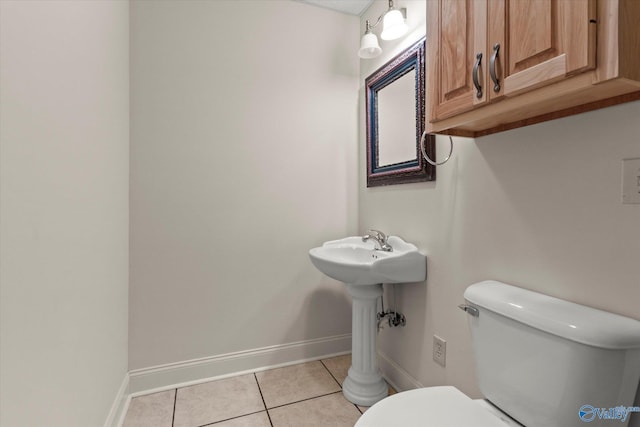 half bath with tile patterned floors, baseboards, and toilet