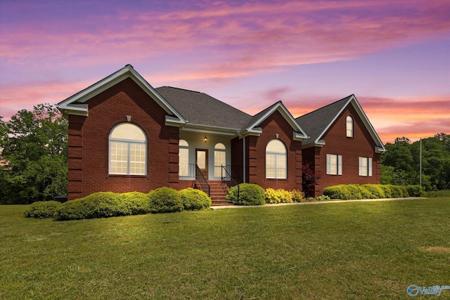 view of front of home featuring brick siding and a yard