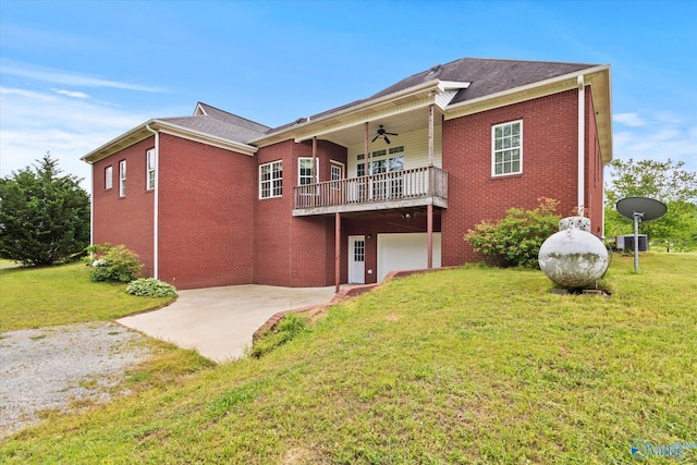 back of house featuring a lawn, an attached garage, ceiling fan, brick siding, and driveway