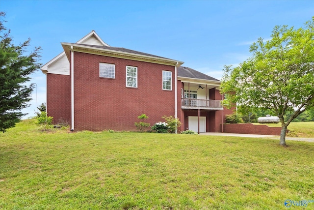 back of property with a ceiling fan, a lawn, an attached garage, and a balcony