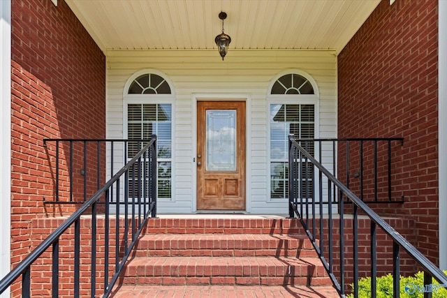 doorway to property featuring brick siding and covered porch