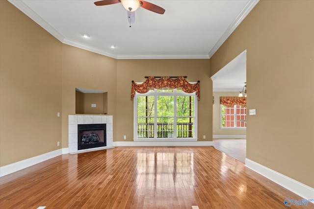 unfurnished living room featuring crown molding, hardwood / wood-style floors, ceiling fan, a fireplace, and baseboards