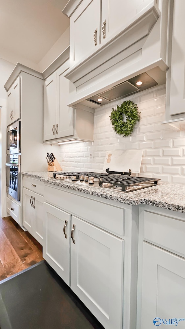 17583 Maree Dr, Athens, AL 35613 - kitchen with white cabinetry, tasteful backsplash, appliances with stainless steel finishes, premium range hood, and light stone counters