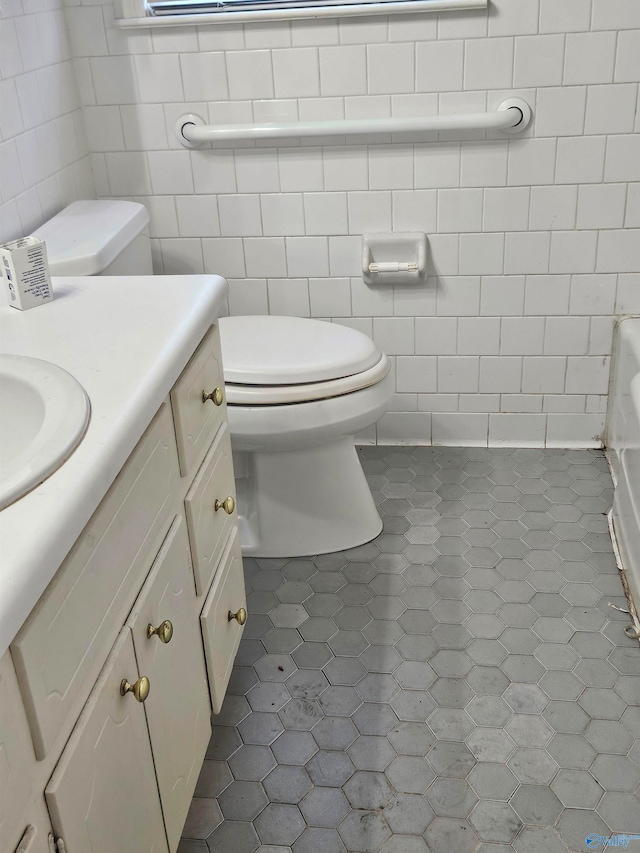 bathroom featuring toilet, vanity, tile patterned floors, and tile walls