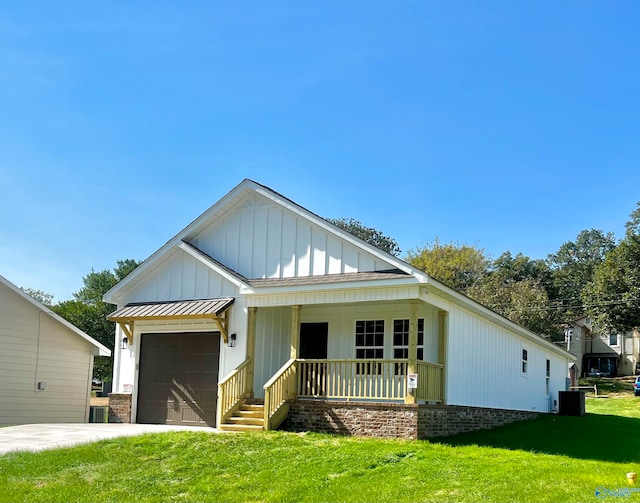 view of front of home featuring central air condition unit, covered porch, a front yard, and a garage