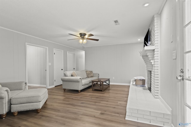 3374 Old Moulton Rd SW, Decatur, AL 35603 - living room featuring a ceiling fan, a fireplace, wood finished floors, ornamental molding, and a decorative wall