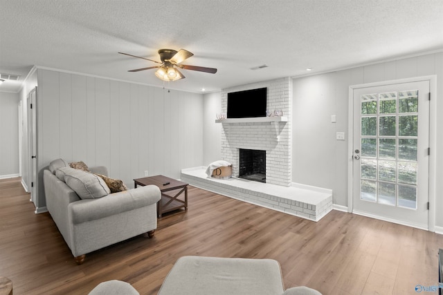 living room with a textured ceiling, a fireplace, hardwood / wood-style flooring, and ceiling fan