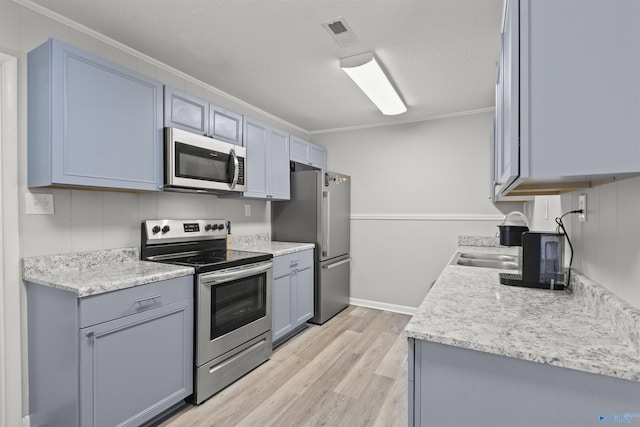 3374 Old Moulton Rd SW, Decatur, AL 35603 - kitchen with appliances with stainless steel finishes, light wood-style floors, crown molding, light countertops, and gray cabinetry