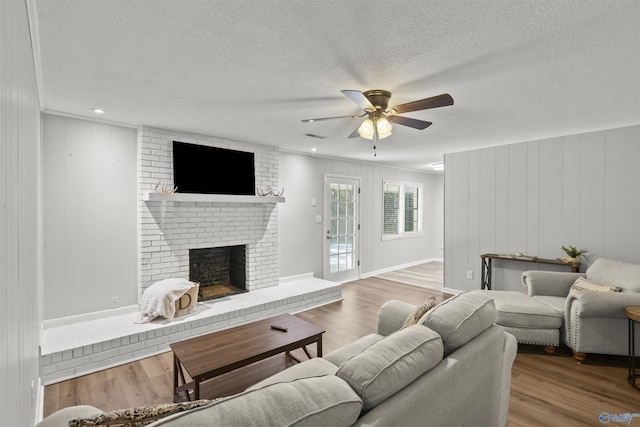 3374 Old Moulton Rd SW, Decatur, AL 35603 - living room featuring a ceiling fan, wood finished floors, a fireplace, and a textured ceiling