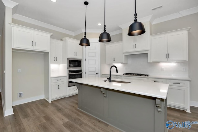 kitchen with built in microwave, sink, white cabinetry, stainless steel oven, and pendant lighting