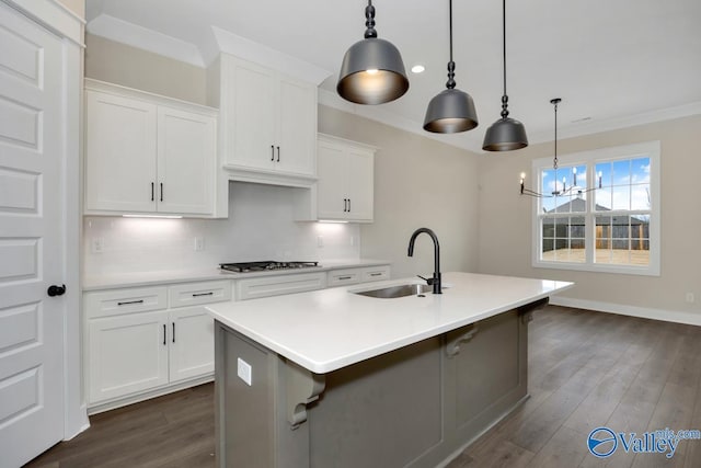 kitchen with a kitchen island with sink, sink, hanging light fixtures, and white cabinets