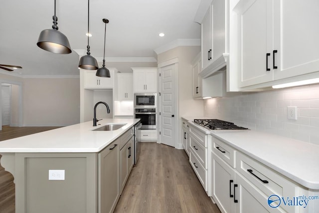 kitchen with stainless steel appliances, an island with sink, sink, and white cabinets