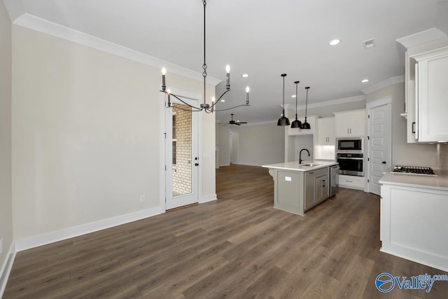 kitchen with pendant lighting, crown molding, appliances with stainless steel finishes, a kitchen island with sink, and white cabinets