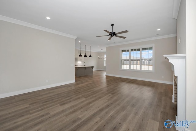 unfurnished living room featuring crown molding, sink, dark hardwood / wood-style flooring, and ceiling fan with notable chandelier