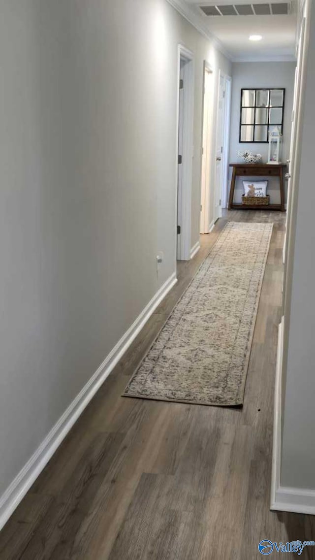 hallway featuring visible vents, ornamental molding, baseboards, and wood finished floors