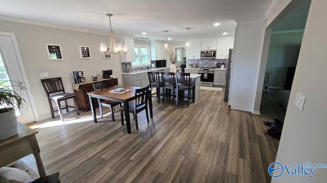 dining room with an inviting chandelier, ornamental molding, recessed lighting, dark wood-style flooring, and baseboards