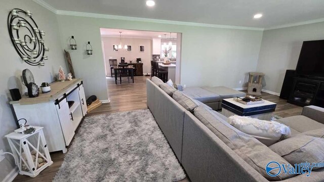 living area featuring crown molding, wood finished floors, baseboards, and recessed lighting