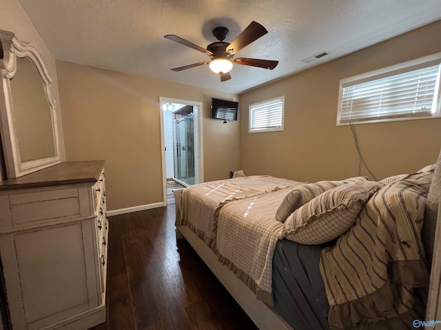 bedroom with a textured ceiling, ceiling fan, dark wood-type flooring, and ensuite bath