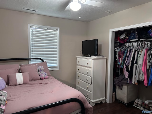 bedroom featuring ceiling fan, a closet, dark wood-type flooring, and a textured ceiling