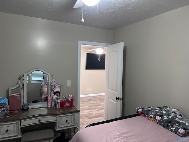 bedroom with ceiling fan, a textured ceiling, and light wood-type flooring