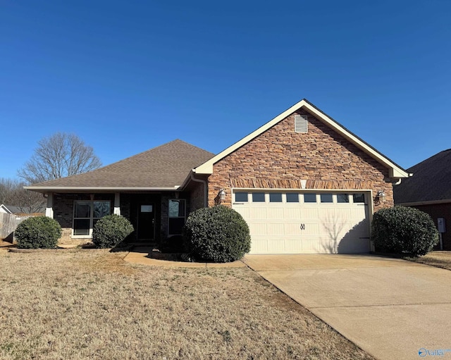 ranch-style home featuring roof with shingles, a front yard, a garage, stone siding, and driveway