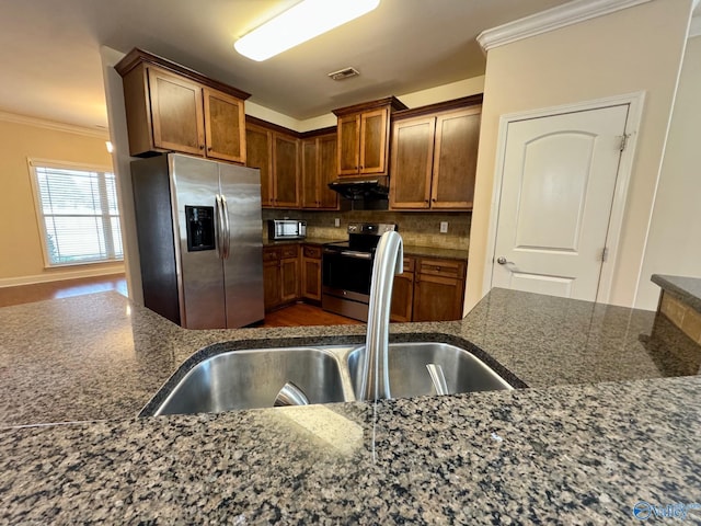 kitchen featuring stainless steel appliances, exhaust hood, visible vents, backsplash, and crown molding