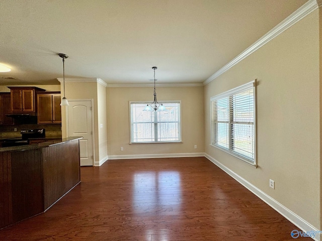 kitchen featuring dark wood-style flooring, baseboards, ornamental molding, dark countertops, and decorative light fixtures