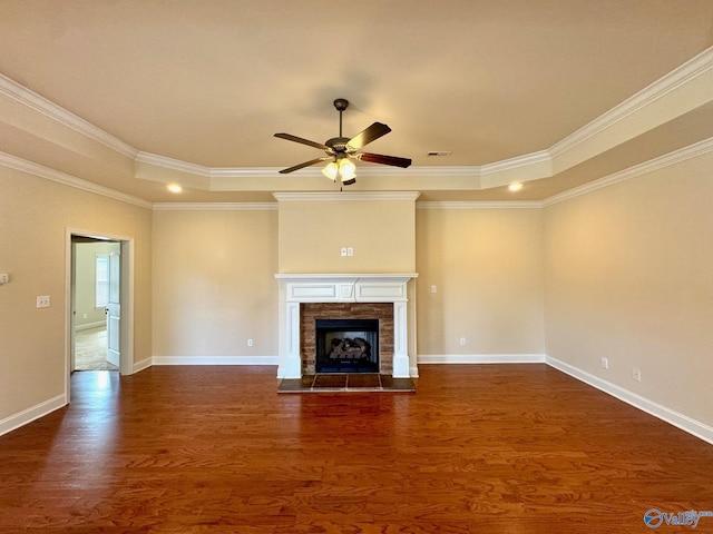 unfurnished living room featuring a fireplace with flush hearth, a tray ceiling, dark wood finished floors, and baseboards