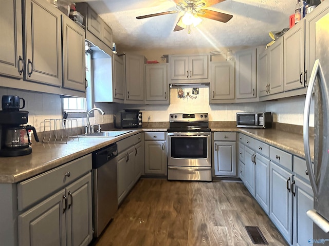 kitchen featuring gray cabinets, appliances with stainless steel finishes, sink, and dark wood-type flooring