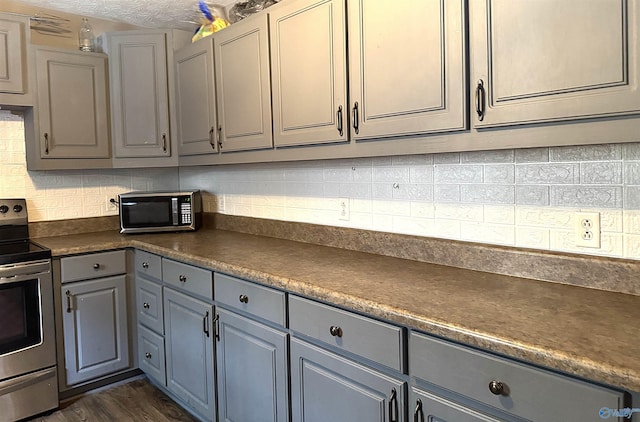 kitchen with backsplash, gray cabinetry, a textured ceiling, stainless steel appliances, and dark hardwood / wood-style flooring