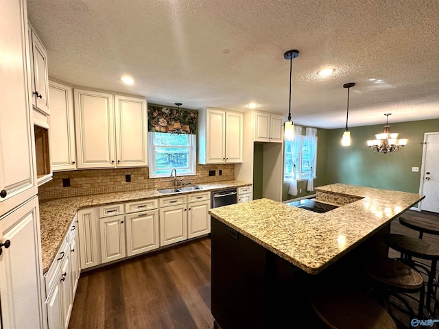 kitchen featuring a chandelier, dark wood-type flooring, decorative light fixtures, sink, and a center island