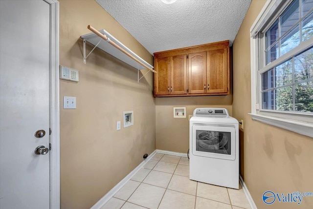 clothes washing area featuring cabinet space, light tile patterned flooring, a textured ceiling, washer / dryer, and baseboards