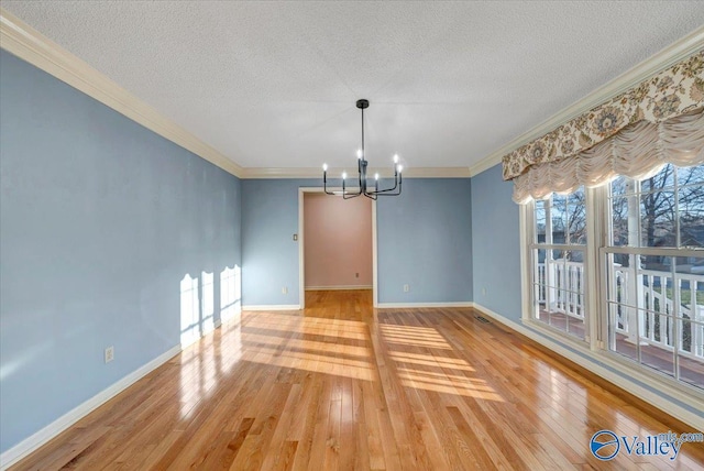 unfurnished dining area featuring a chandelier, wood-type flooring, baseboards, and crown molding