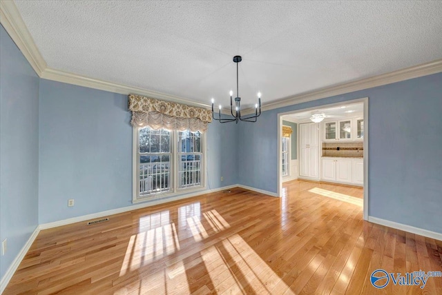 unfurnished dining area with wood-type flooring, visible vents, a notable chandelier, and a textured ceiling