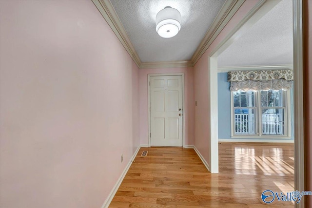 entryway featuring a textured ceiling, light wood-type flooring, baseboards, and crown molding