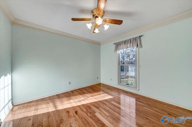 spare room with visible vents, crown molding, a textured ceiling, and wood finished floors