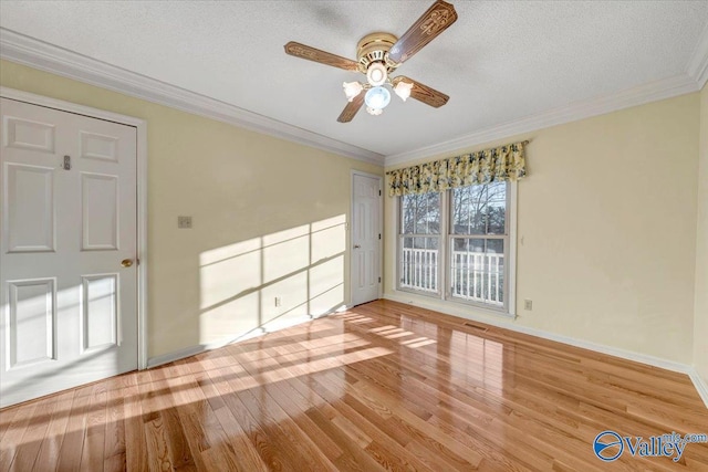 spare room with baseboards, a textured ceiling, ornamental molding, and wood finished floors