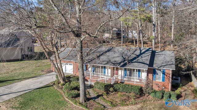 view of front facade featuring brick siding, covered porch, a front yard, a garage, and driveway