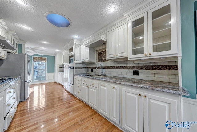 kitchen with a wainscoted wall, white cabinets, and a sink