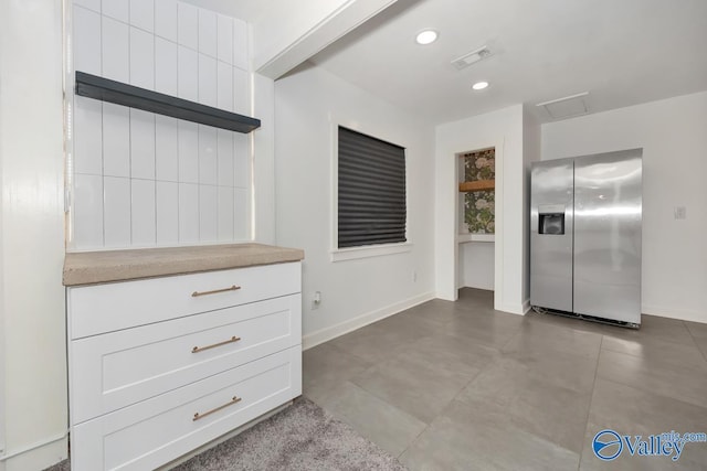 kitchen with visible vents, baseboards, stainless steel fridge, recessed lighting, and white cabinetry