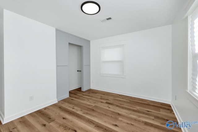 unfurnished bedroom with visible vents, baseboards, and wood finished floors
