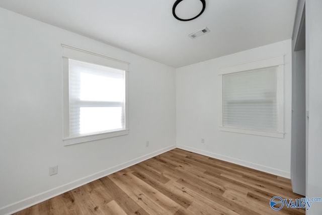 spare room featuring visible vents, baseboards, and wood finished floors