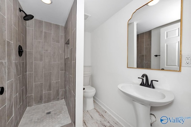 full bathroom featuring toilet, baseboards, and a tile shower