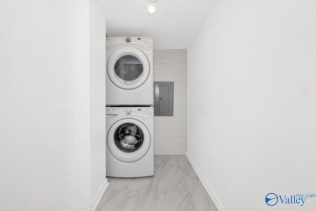 laundry room featuring laundry area, stacked washer and dryer, marble finish floor, and electric panel