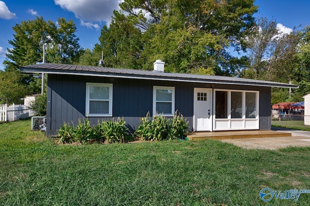 back of house with a lawn, fence, a chimney, and metal roof