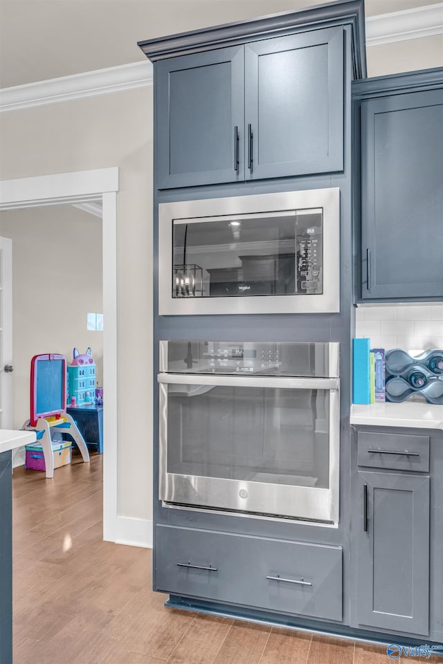 interior space with crown molding, light hardwood / wood-style flooring, tasteful backsplash, built in microwave, and stainless steel oven