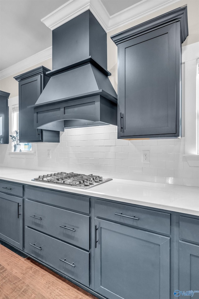 kitchen with ornamental molding, light hardwood / wood-style floors, stainless steel gas stovetop, and premium range hood