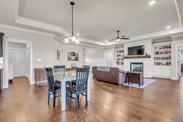 dining space featuring ceiling fan, wood-type flooring, a tray ceiling, and ornamental molding