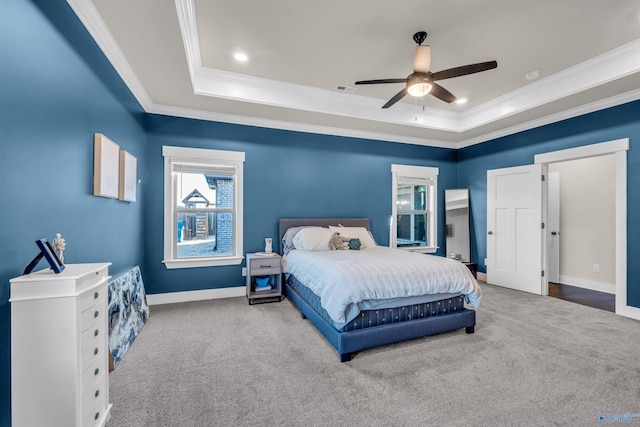 carpeted bedroom with ceiling fan, ornamental molding, and a raised ceiling