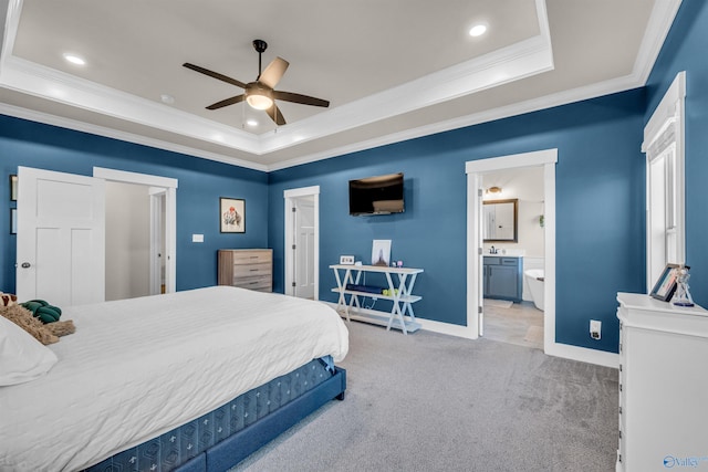 carpeted bedroom with ceiling fan, ensuite bath, ornamental molding, and a tray ceiling